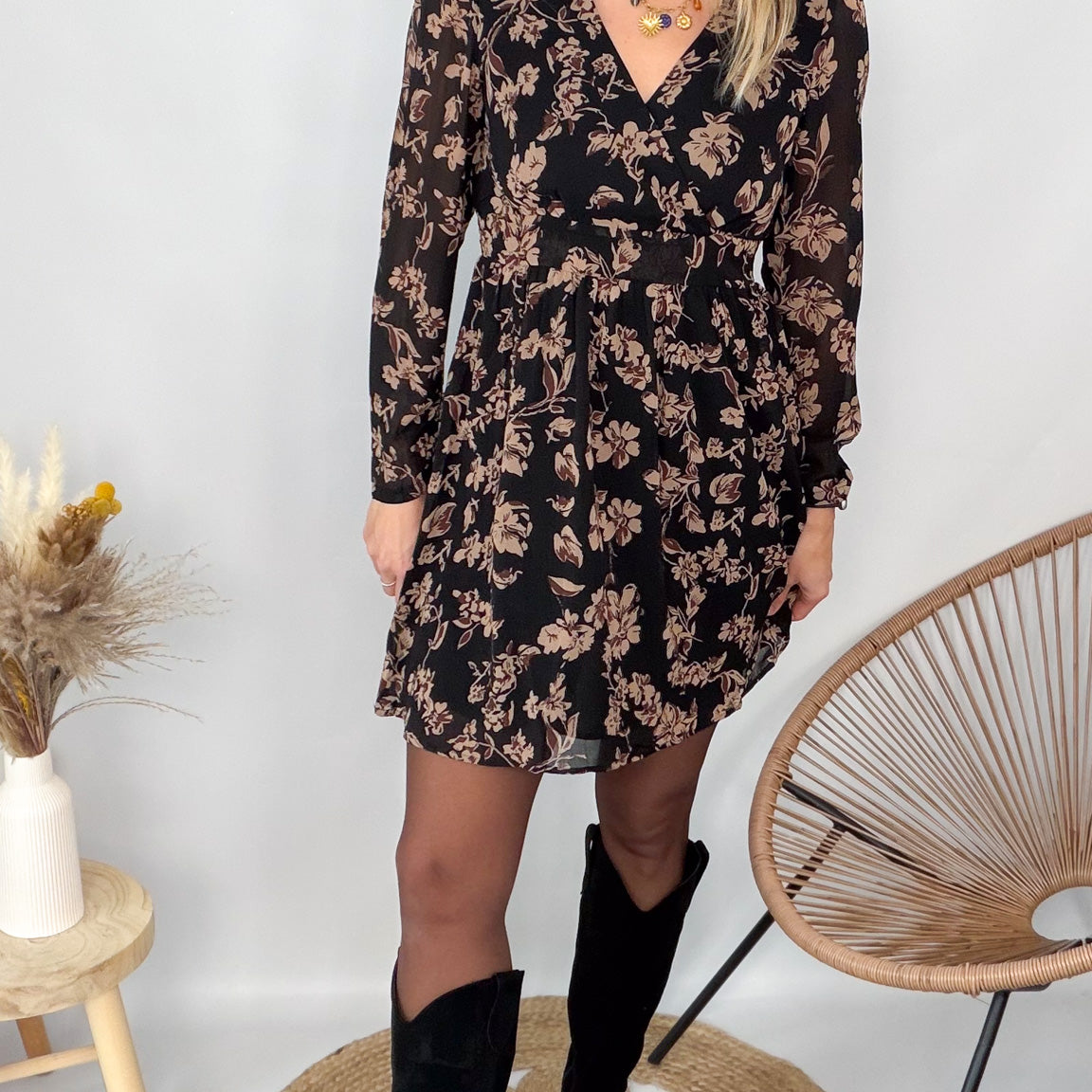Femme portant une robe noire courte à fleurs avec des bottes noires - Prêt-à-porter La Boutique de Lydie.