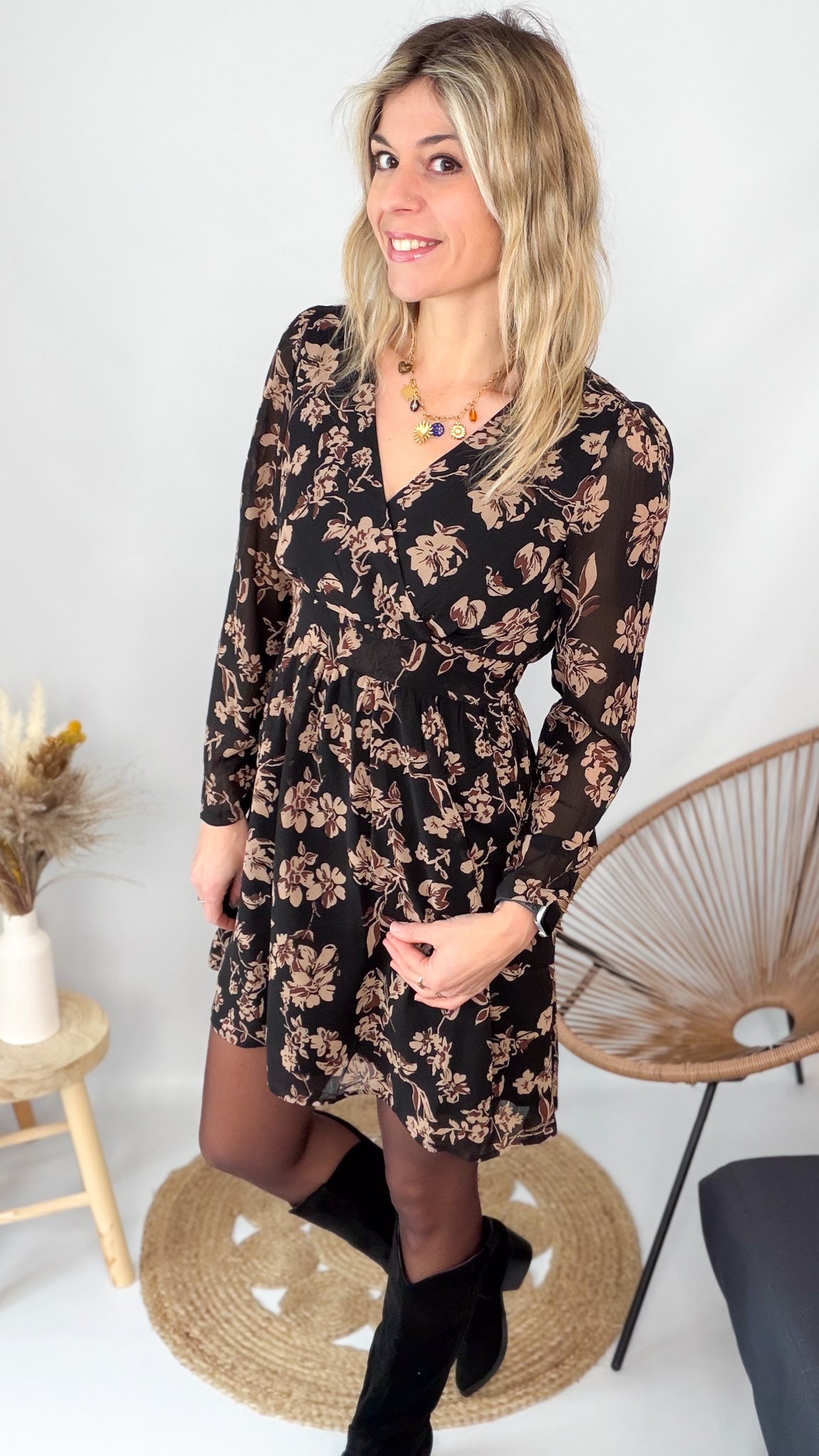 Femme portant une robe noire courte à fleurs avec des bottes noires - Prêt-à-porter La Boutique de Lydie.