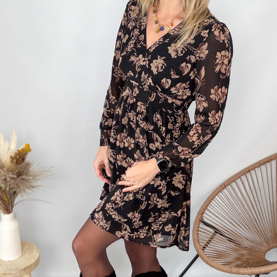 Femme portant une robe noire courte à fleurs avec des bottes noires - Prêt-à-porter La Boutique de Lydie.