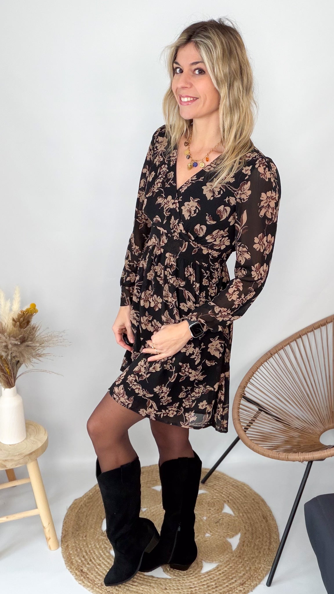 Femme portant une robe noire courte à fleurs avec des bottes noires - Prêt-à-porter La Boutique de Lydie.