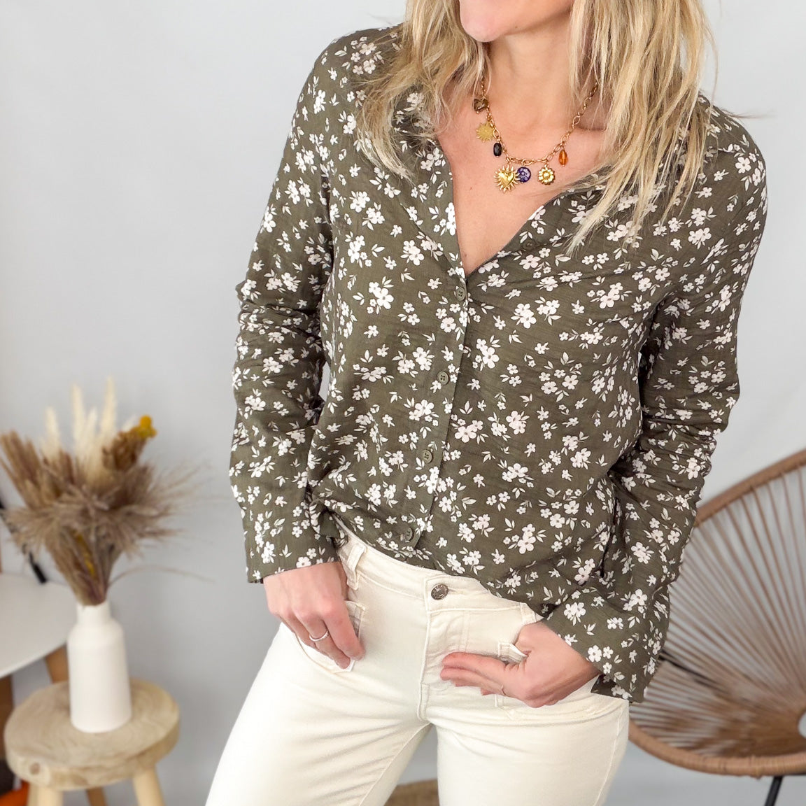 Femme portant une chemise kaki à fleurs blanches et un pantalon blanc - La Boutique de Lydie.