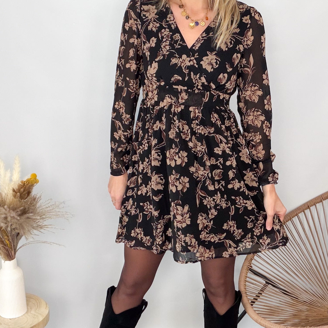 Femme portant une robe noire courte à fleurs avec des bottes noires - Prêt-à-porter La Boutique de Lydie.