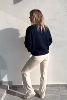 Pull bleu marine avec motif 'amour' cœur fleuri, boutons décoratifs sur l'épaule, porté avec un jean écru et des baskets blanches.