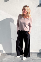 Pantalon large noir taille haute, coupe fluide, porté avec un pull taupe et des baskets blanches, look confortable et élégant.