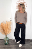 Pantalon large noir taille haute, coupe fluide, porté avec un pull taupe et des baskets blanches, look confortable et élégant.
