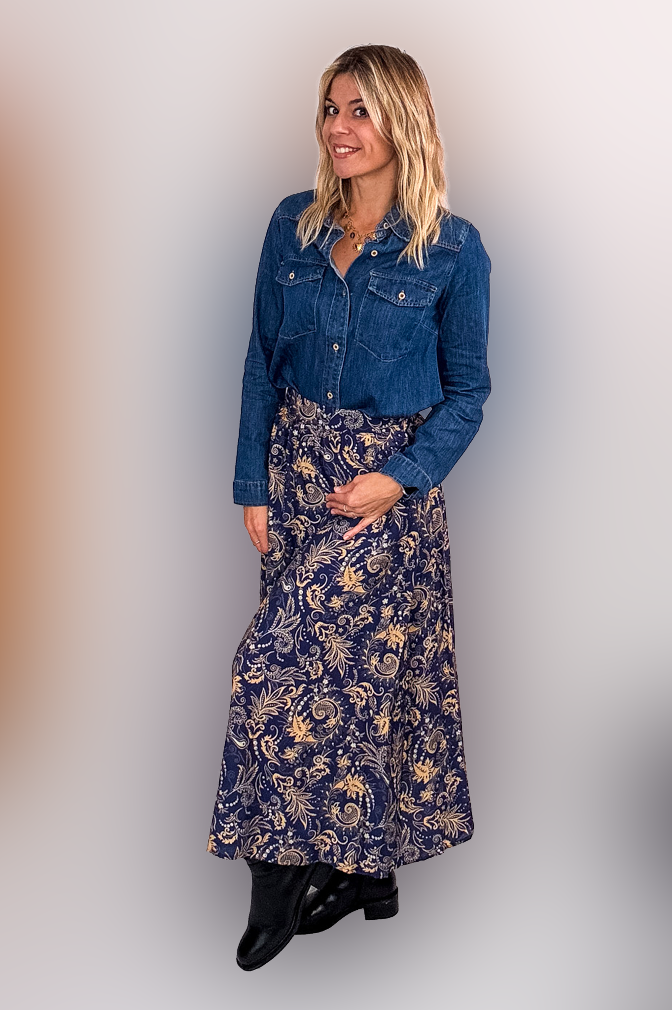 Jupe longue fluide motif cachemire bleu marine et or, portée avec une chemise en jean et des bottines noires.