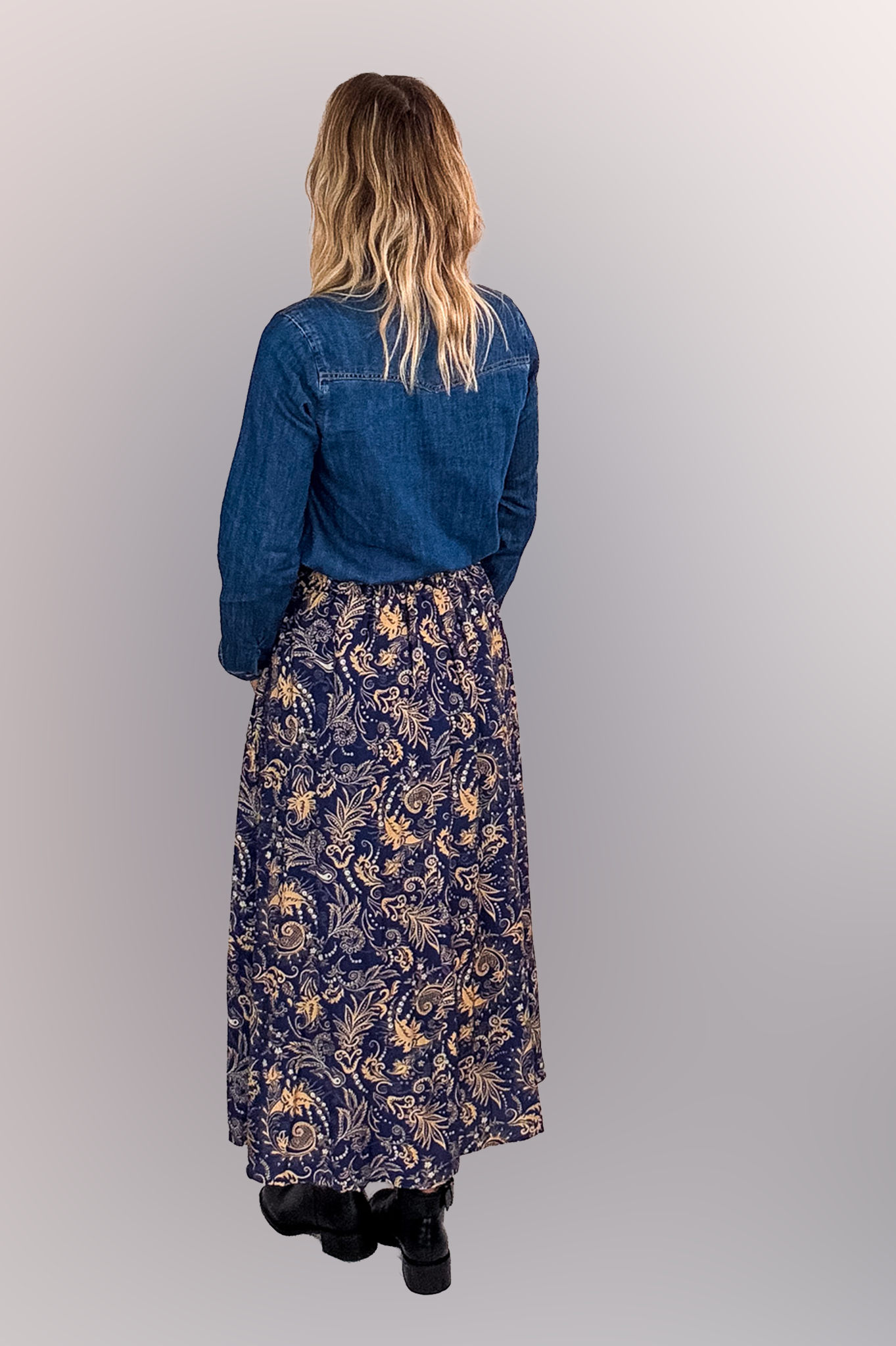 Jupe longue fluide motif cachemire bleu marine et or, portée avec une chemise en jean et des bottines noires.