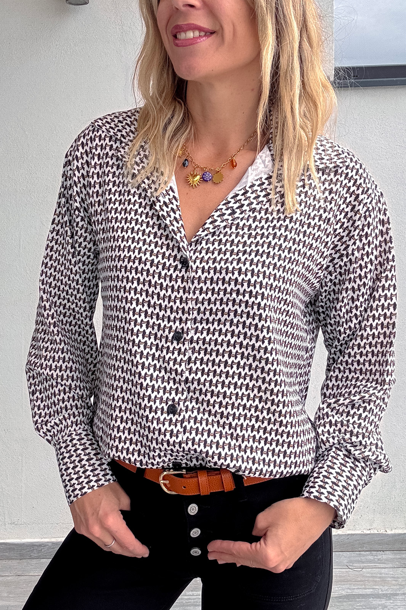 Gros plan Chemise motif pied-de-poule noir et blanc, boutons noirs, et collier multicharmes