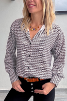 Gros plan Chemise motif pied-de-poule noir et blanc, boutons noirs, et collier multicharmes