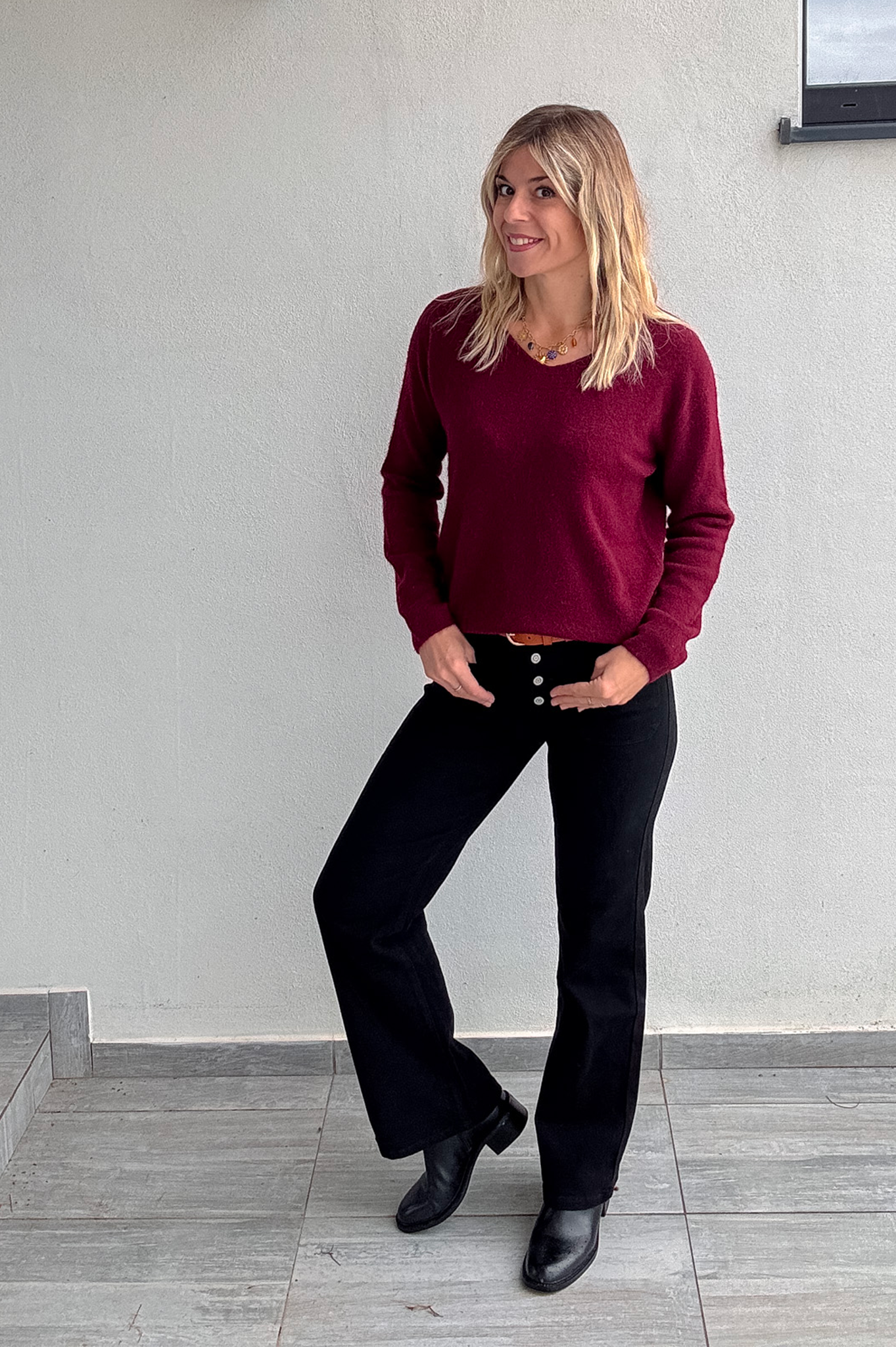 Pull bordeaux col V en maille douce, Taille Unique, porté rentré dans un jean noir taille haute avec une ceinture camel