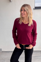 Pull bordeaux col V en maille douce, Taille Unique, porté rentré dans un jean noir taille haute avec une ceinture camel