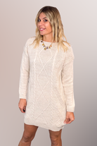 Robe pull courte torsadée couleur écru, portée avec des bottines claires, style d'hiver chic