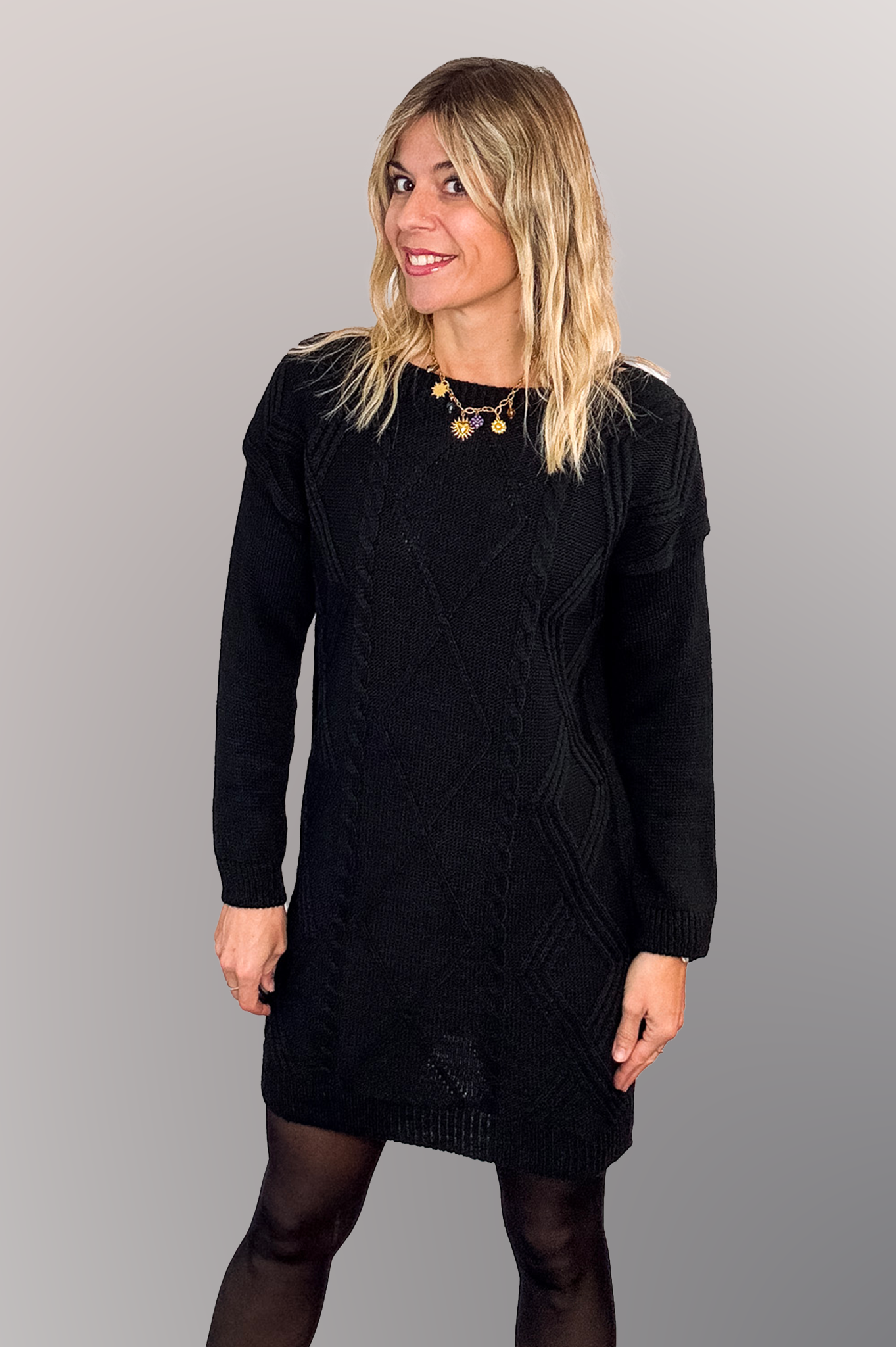 Robe pull courte noire en maille torsadée, des collants noirs et des bottines.