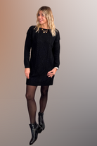 Robe pull courte noire en maille torsadée, des collants noirs et des bottines.