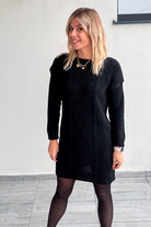 Robe pull courte noire en maille torsadée, des collants noirs et des bottines.