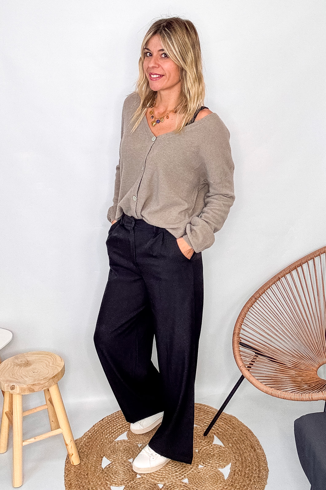 Gilet cardigan taupe maille fine porté rentré dans un pantalon large noir, look chic et confortable.