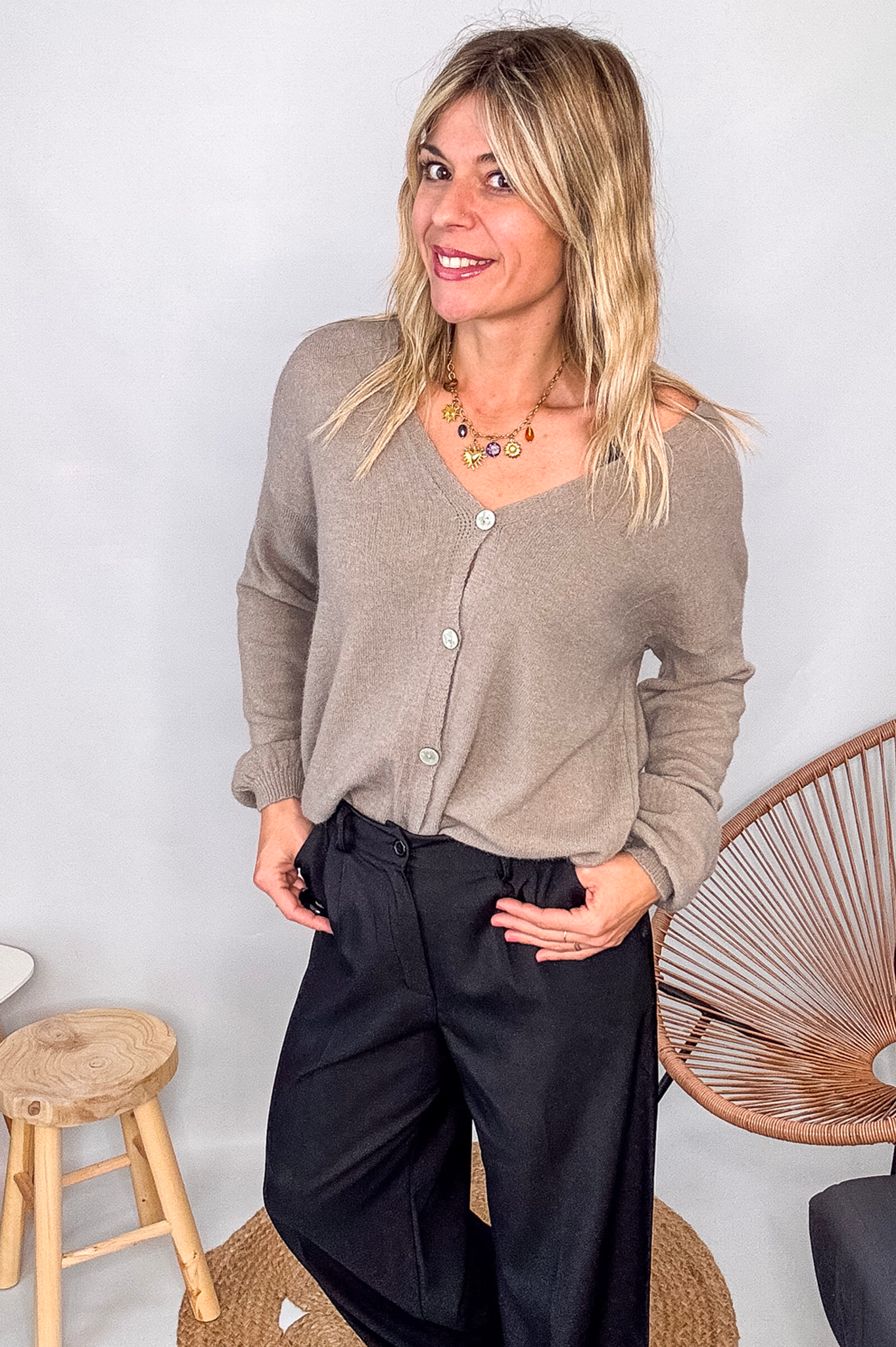 Gilet cardigan taupe maille fine porté rentré dans un pantalon large noir, look chic et confortable.