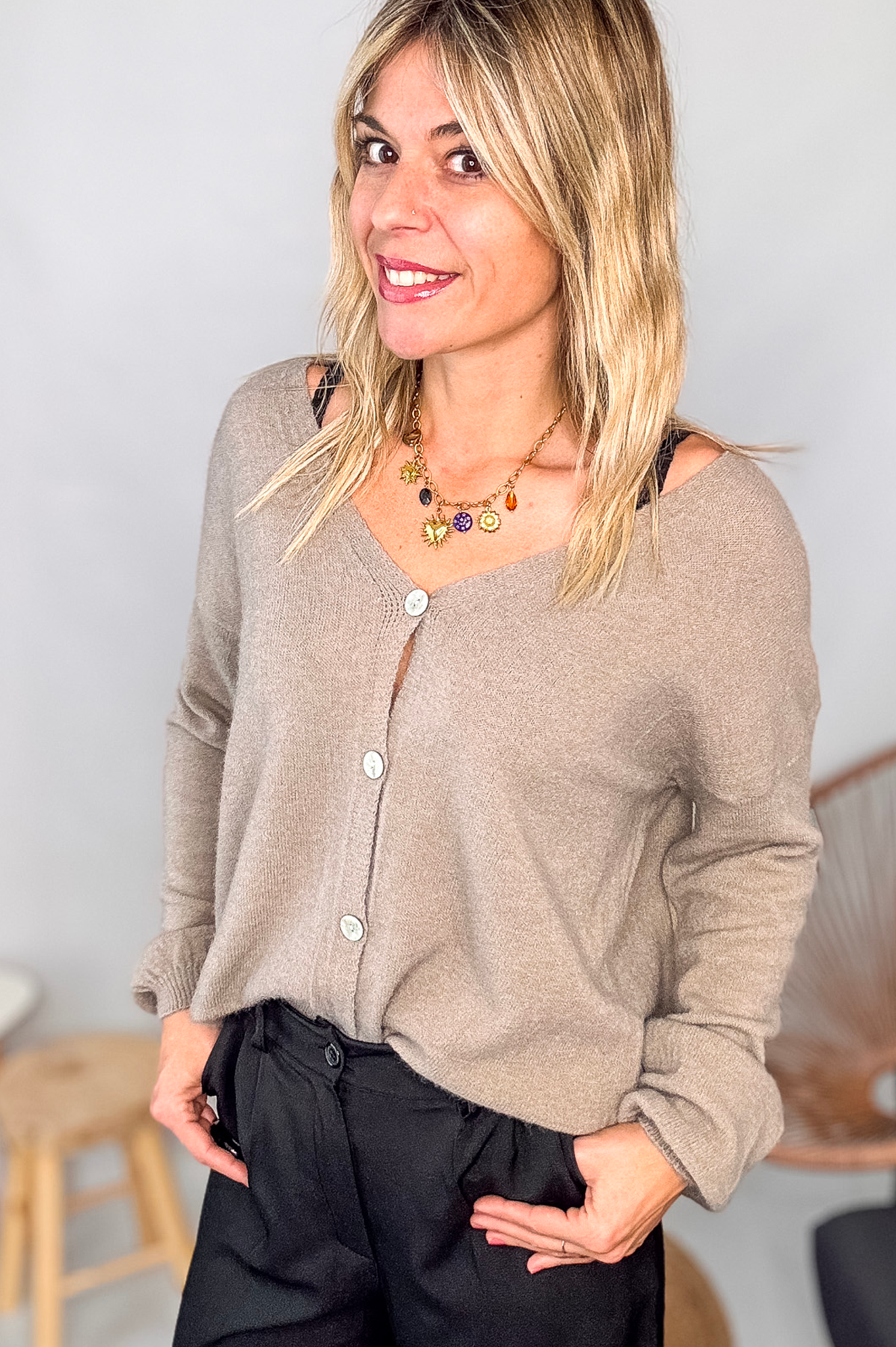 Gilet cardigan taupe maille fine porté rentré dans un pantalon large noir, look chic et confortable.