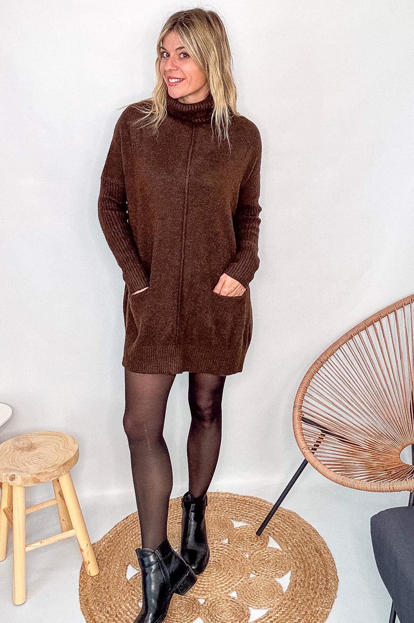 Robe pull marron chocolat col roulé avec poches, coupe ample, portée avec des collants noirs et des bottines.