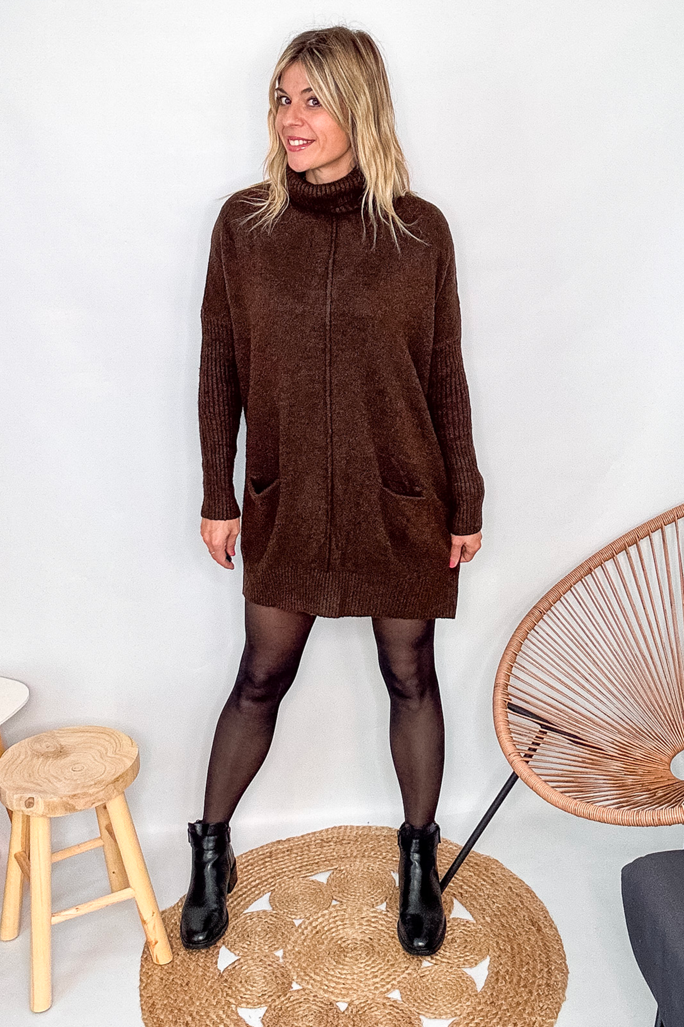 Robe pull marron chocolat col roulé avec poches, coupe ample, portée avec des collants noirs et des bottines.