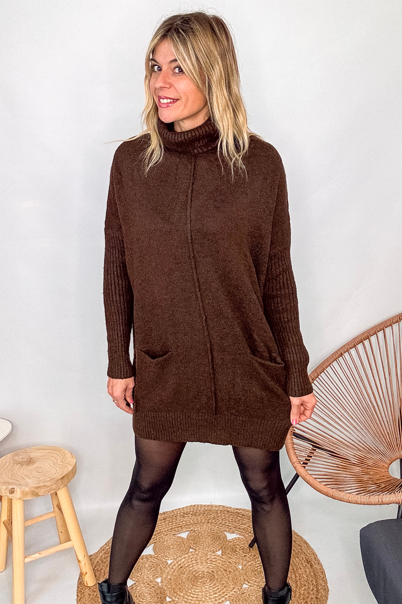 Robe pull marron chocolat col roulé avec poches, coupe ample, portée avec des collants noirs et des bottines.