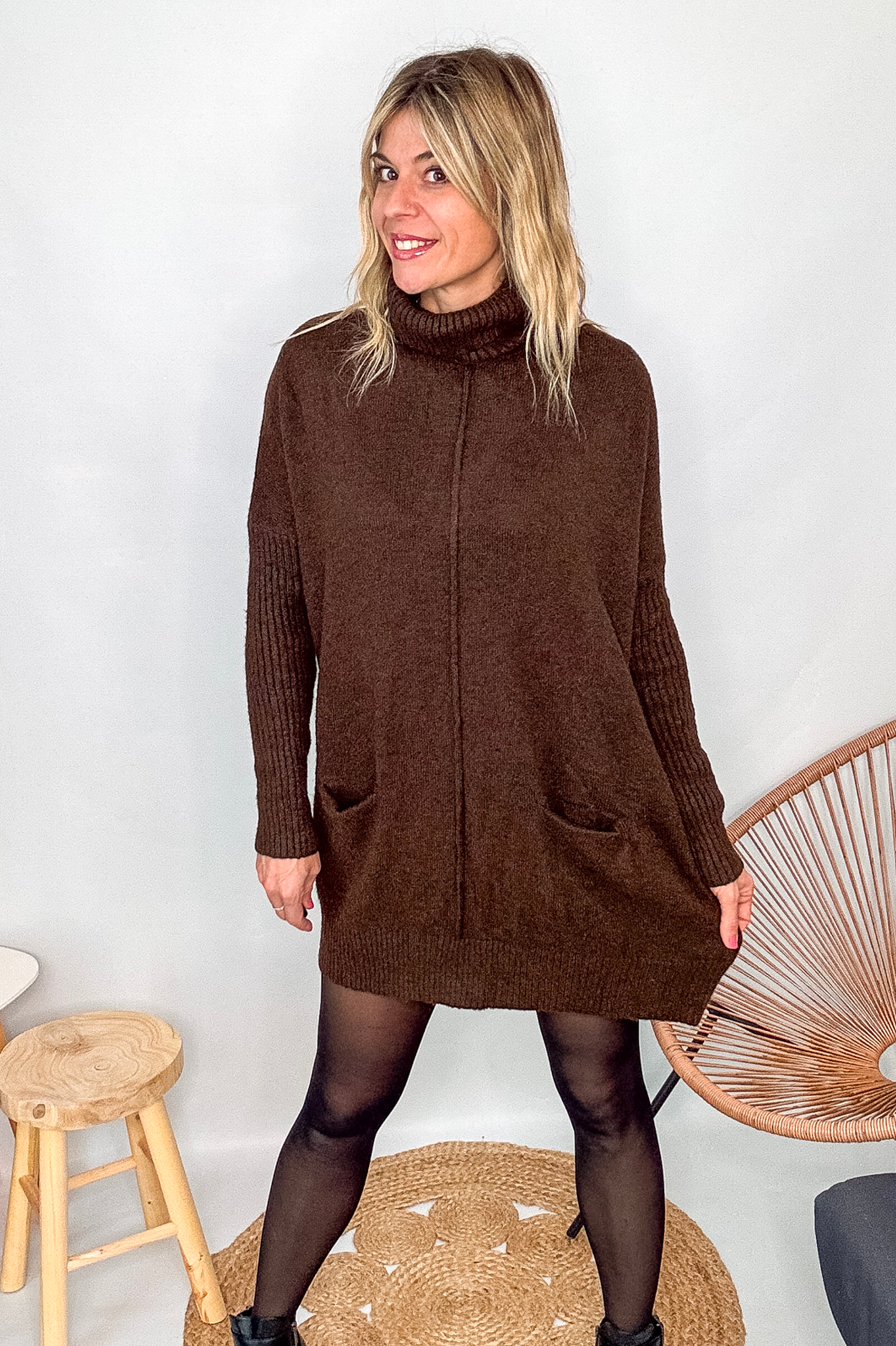 Robe pull marron chocolat col roulé avec poches, coupe ample, portée avec des collants noirs et des bottines.