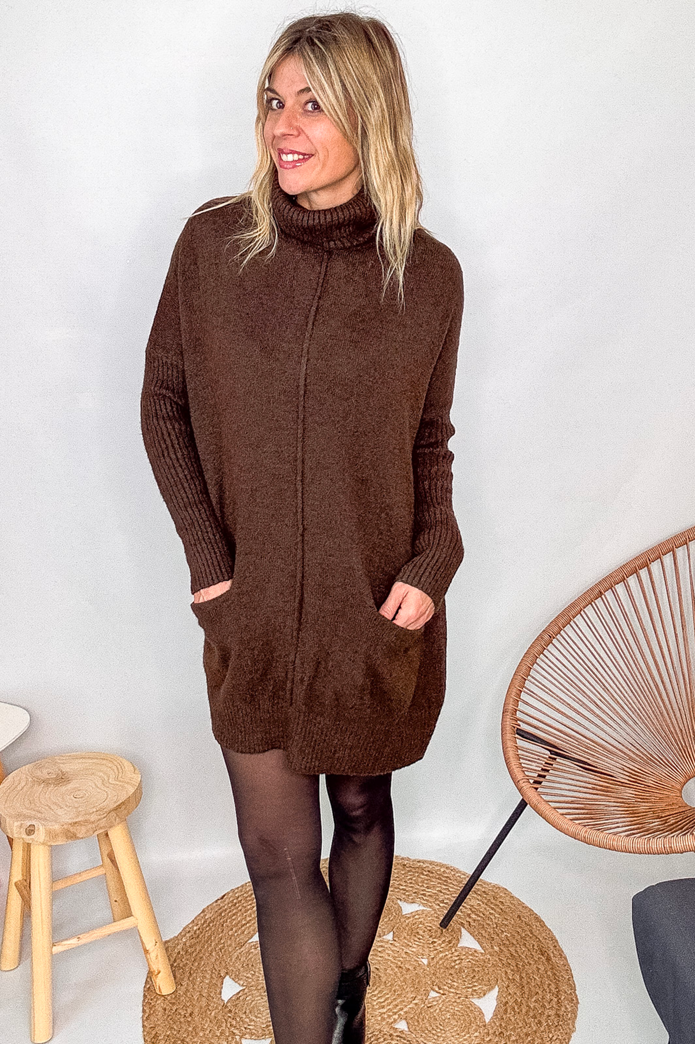 Robe pull marron chocolat col roulé avec poches, coupe ample, portée avec des collants noirs et des bottines.
