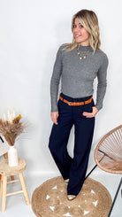 Pull fin gris foncé col rond en maille douce, porté rentré dans un jean noir taille haute avec une ceinture.