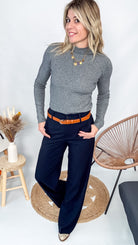 Pull fin gris foncé col rond en maille douce, porté rentré dans un jean noir taille haute avec une ceinture.