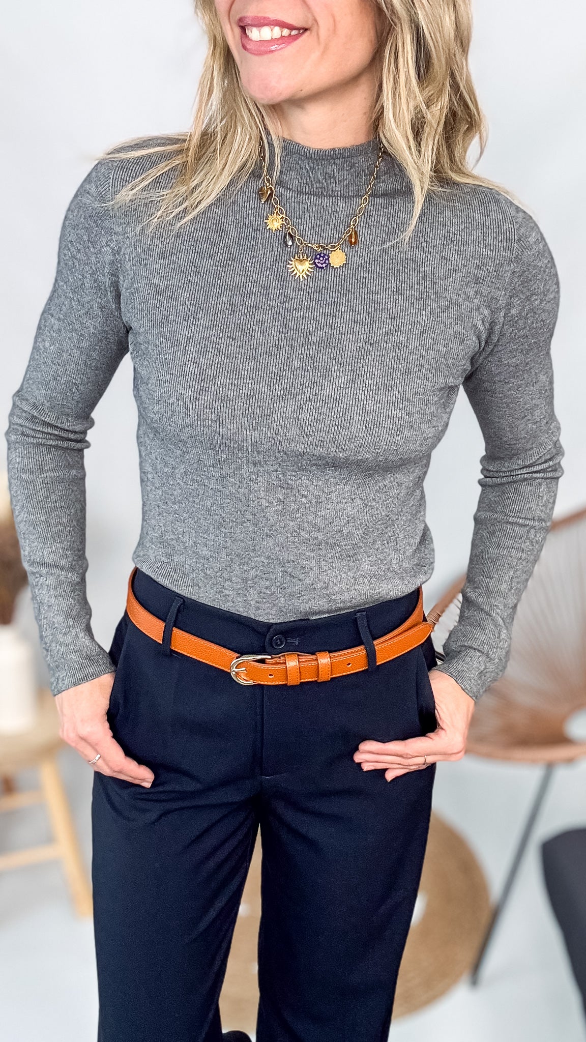 Pull fin gris foncé col rond en maille douce, porté rentré dans un jean noir taille haute avec une ceinture.