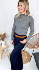 Pull fin gris foncé col rond en maille douce, porté rentré dans un jean noir taille haute avec une ceinture.