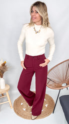 Pull fin beige col rond en maille douce, coupe droite, porté rentré dans un pantalon foncé.