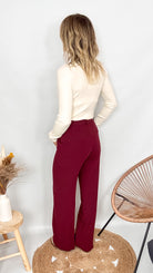 Pantalon tailleur femme bordeaux fluide, coupe droite, porté avec un pull rentré.