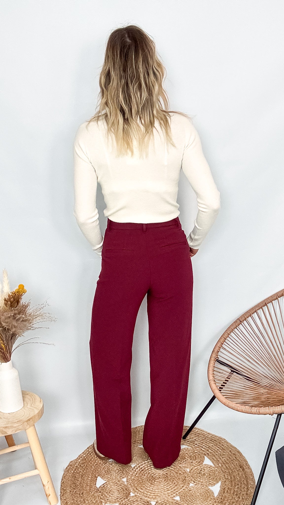 Pantalon tailleur femme bordeaux fluide, coupe droite, porté avec un pull rentré.
