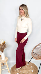 Pantalon tailleur femme bordeaux fluide, coupe droite, porté avec un pull rentré.