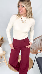 Pull fin beige col rond en maille douce, coupe droite, porté rentré dans un pantalon foncé.