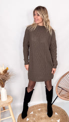 Robe pull maille 100% acrylique couleur marron, coupe droite, portée avec des bottes d'hiver.