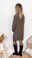 Robe pull maille 100% acrylique, coupe droite, portée avec des bottes d'hiver.