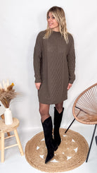 Robe pull maille 100% acrylique couleur marron, coupe droite, portée avec des bottes d'hiver.