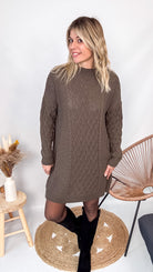 Robe pull maille 100% acrylique couleur marron, coupe droite, portée avec des bottes d'hiver.