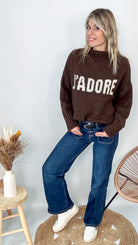 Pull marron col roulé maille, fabriqué en Italie, porté rentré dans un pantalon foncé.