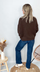 Pull marron col roulé maille, fabriqué en Italie, porté rentré dans un pantalon foncé.