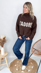 Pull marron col roulé maille, fabriqué en Italie, porté rentré dans un pantalon foncé.