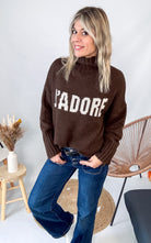 Pull marron col roulé maille, fabriqué en Italie, porté rentré dans un pantalon foncé.