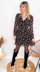 Robe noire fleurie 100% polyester, coupe fluide, portée avec des collants et des bottines.