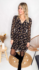 Robe noire fleurie 100% polyester, coupe fluide, portée avec des collants et des bottines.