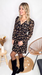 Robe noire fleurie 100% polyester, coupe fluide, portée avec des collants et des bottines.