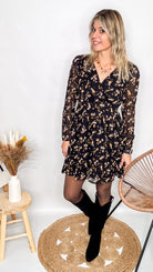 Robe noire fleurie 100% polyester, coupe fluide, portée avec des collants et des bottines.