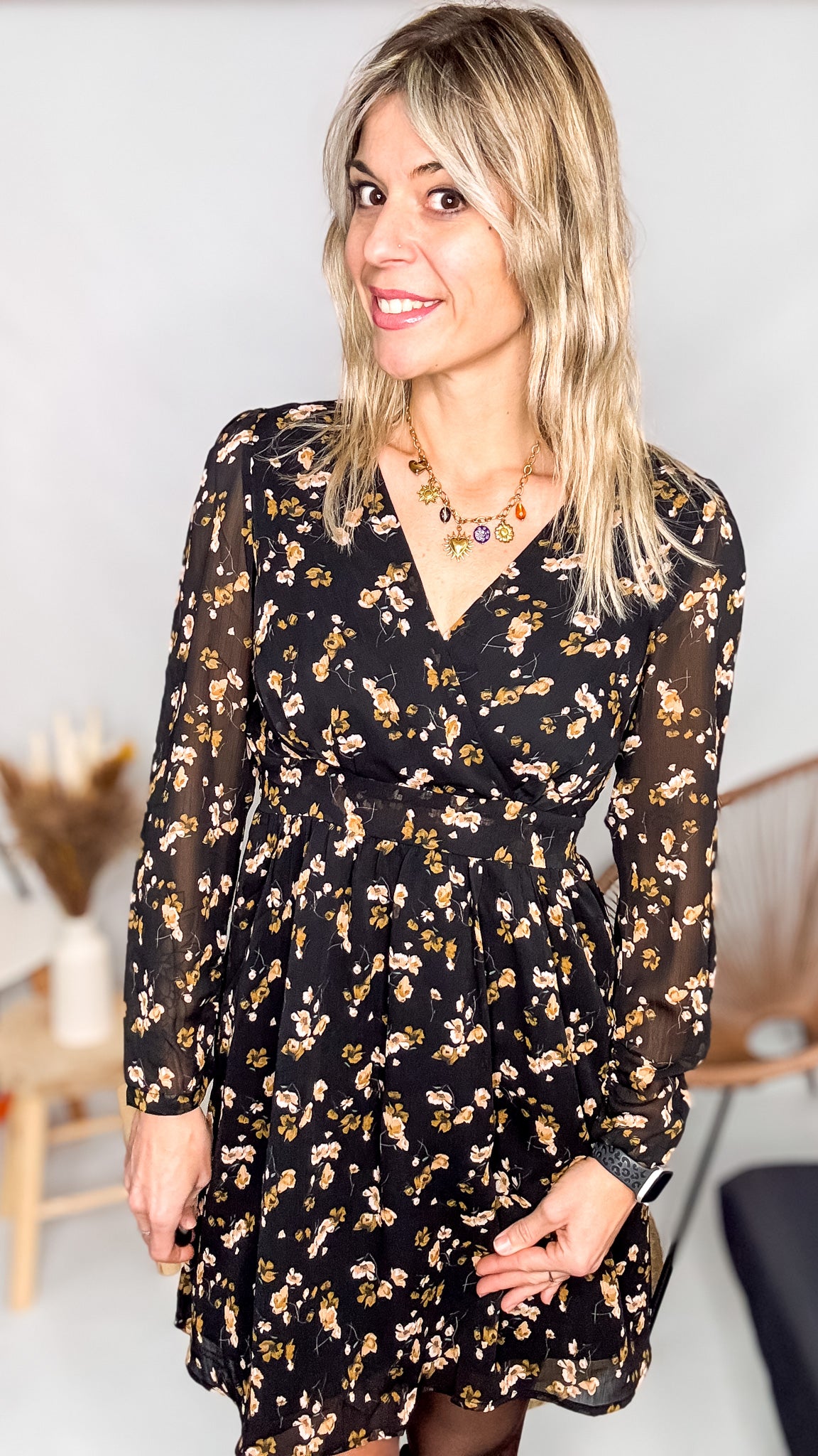 Robe noire fleurie 100% polyester, coupe fluide, portée avec des collants et des bottines.