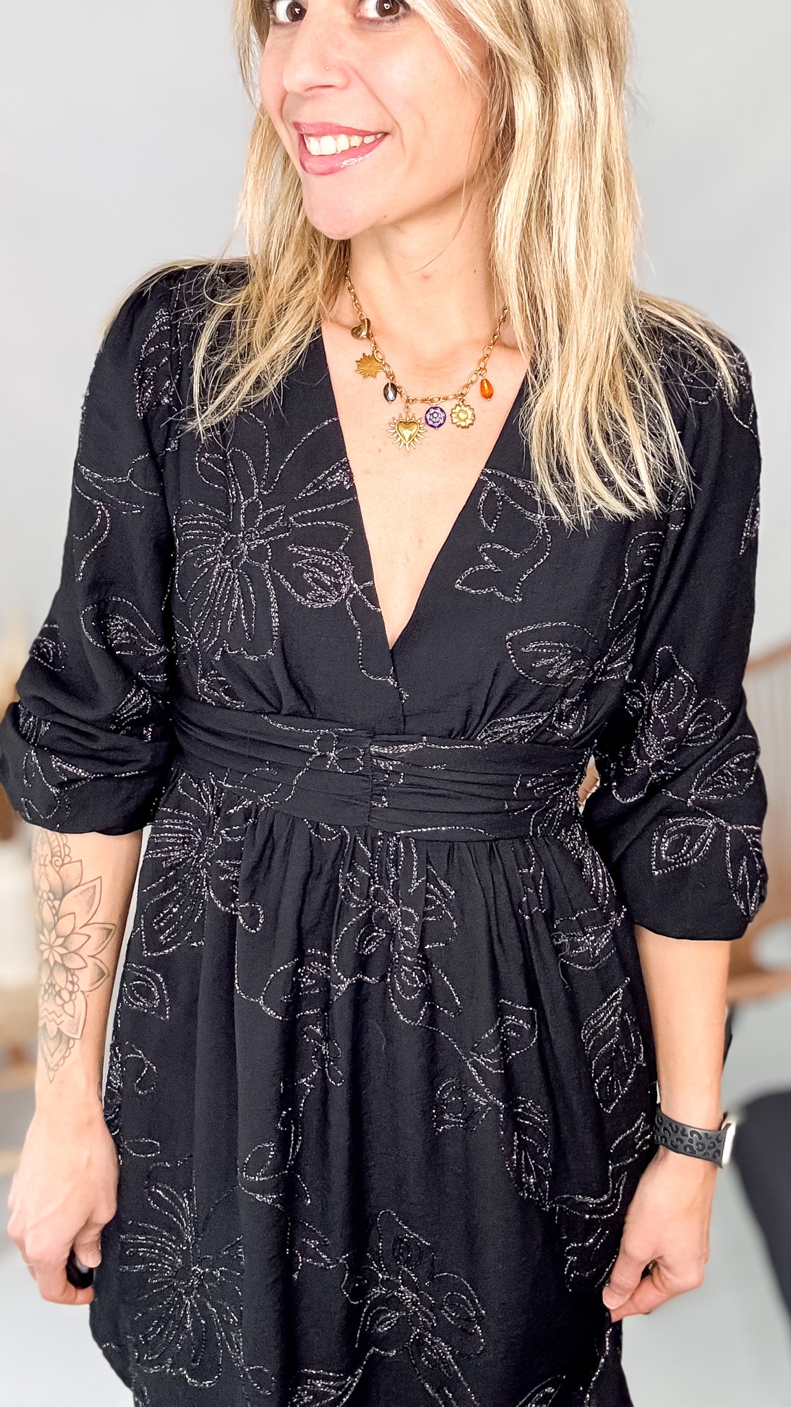 Détail décolleté croisé col V et collier doré sur robe noire brodée